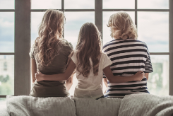 three women of different ages sitting on the back of a couch